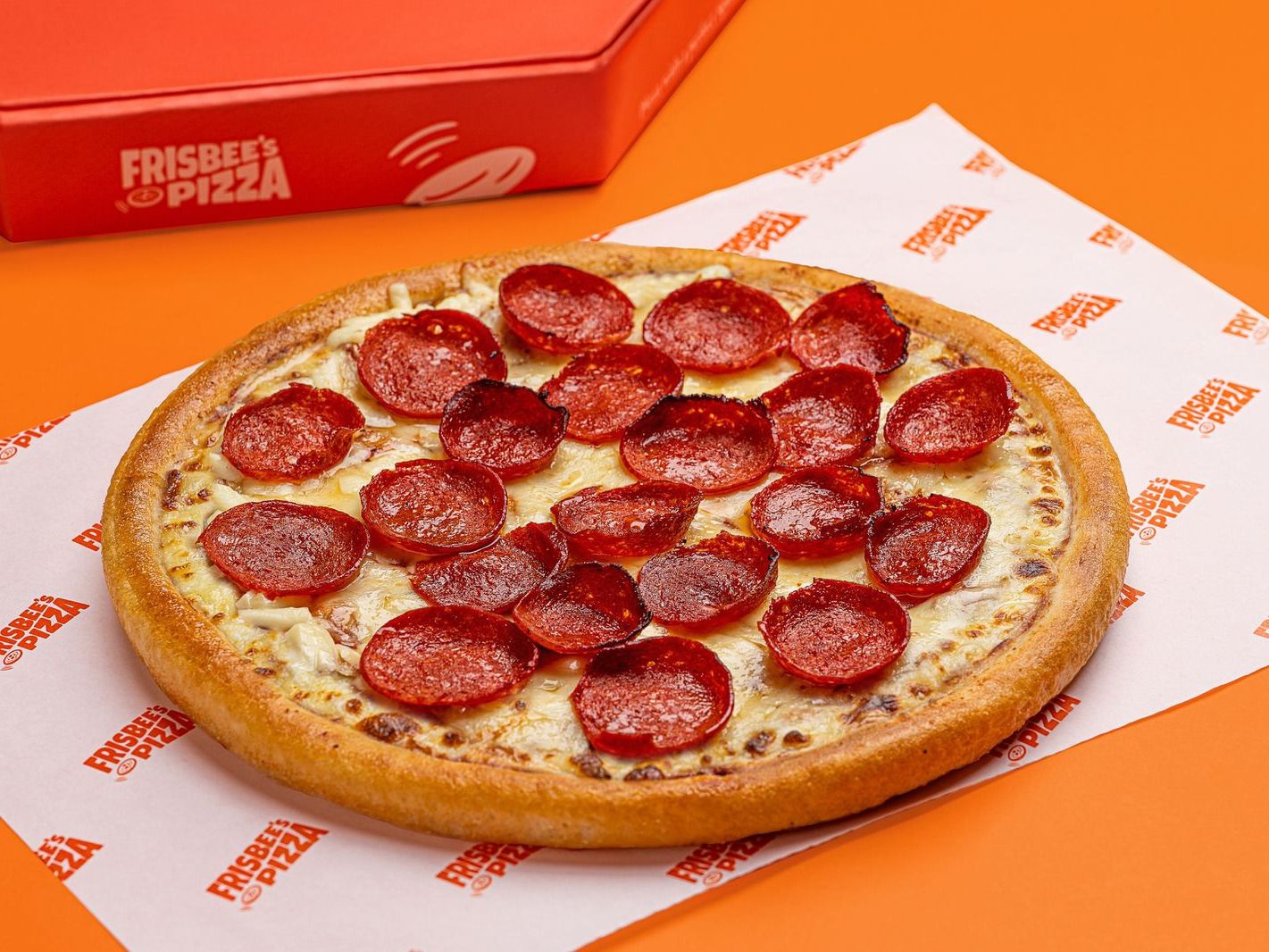 Frisbee's pepperoni pan pizza on branded paper beside a Frisbee's box
